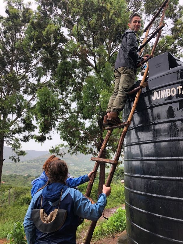 Study abroad alumni standing on ladder leaning on a water tank