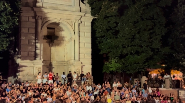 Photo of Italian crowd settled under a large fountain at night