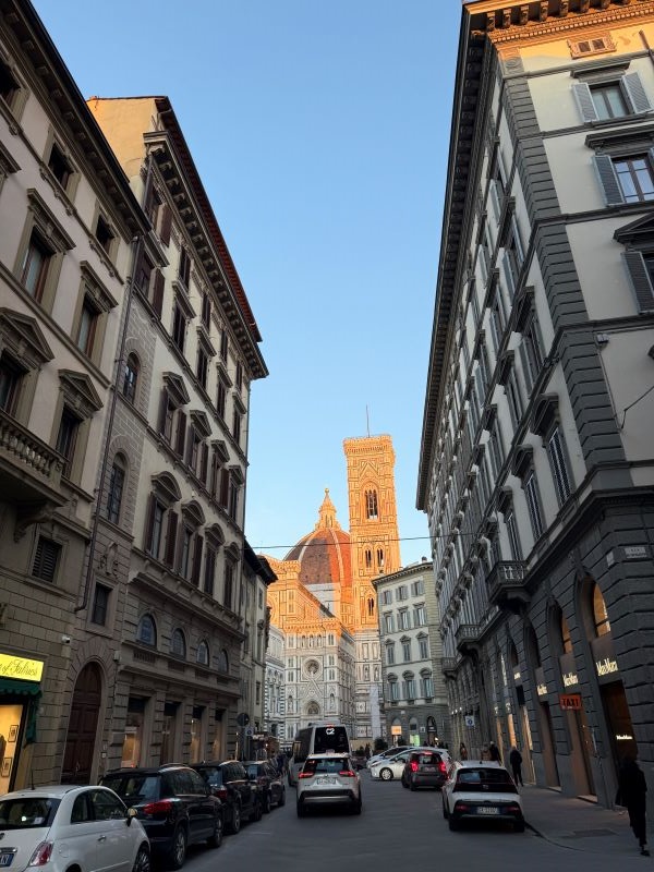 Busy Florence street with the Duomo peaking through buildings