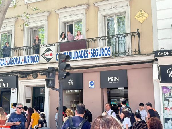 Crowded street with people on balcony