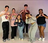 Students taking selfie as they pose with hands making heart shapes
