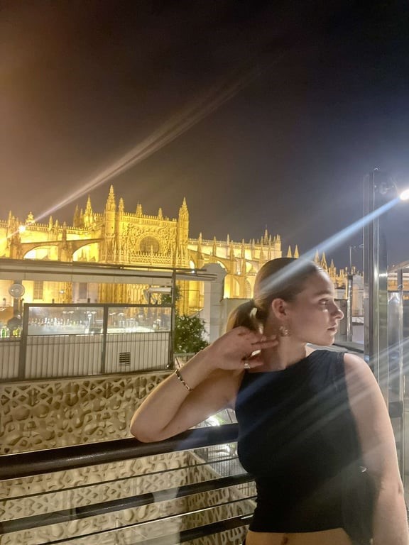 A study abroad student leaning on a railing with a castle in the background