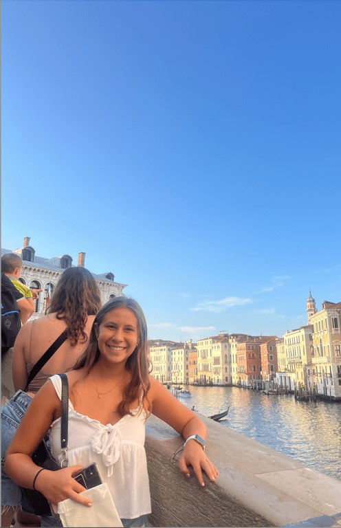 A study abroad student smiling at the camera near a body of water