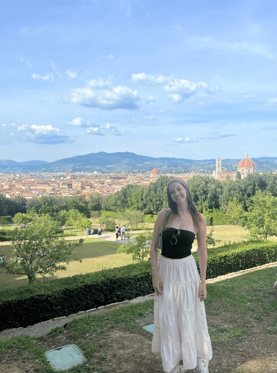 a study abroad student standing in a park with a city in the background