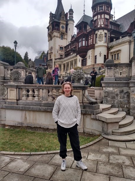 a study abroad student standing in front of a castle
