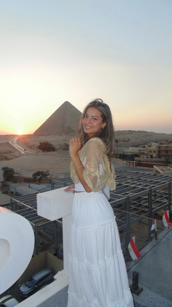 A study abroad smiling at the camera with a large pyramid in the background