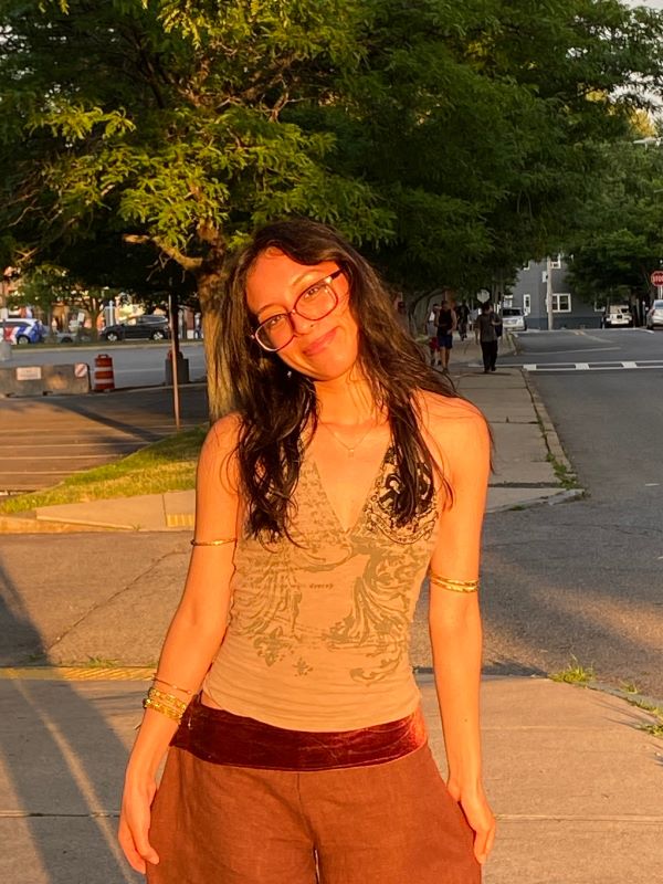A study abroad student smiling at the camera in an outdoor setting while bathed in late-day sunlight