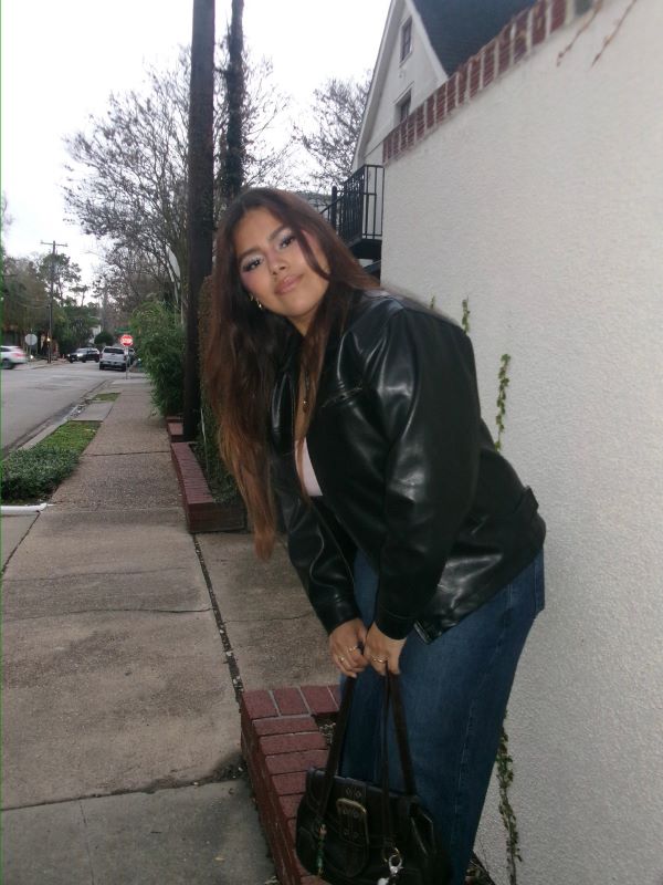 A study abroad student standing outdoors and holding a small black purse while smiling at the camera