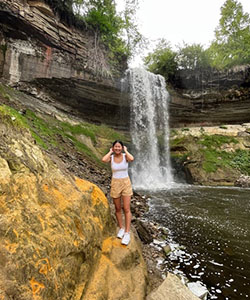 A person standing on a rock near a waterfall