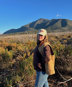 A person standing in a field with mountains in the background