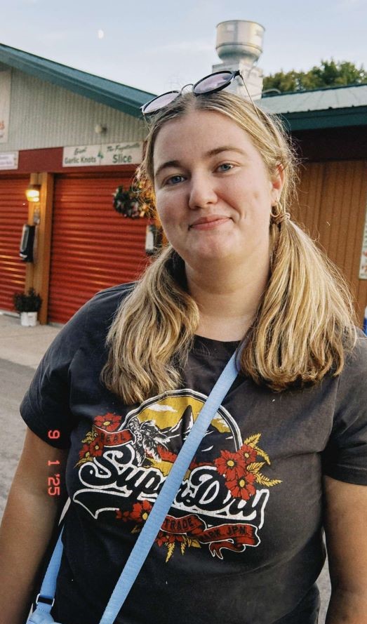 A study abroad student with blonde hair in two low ponytails standing outdoors and smiling at the camera