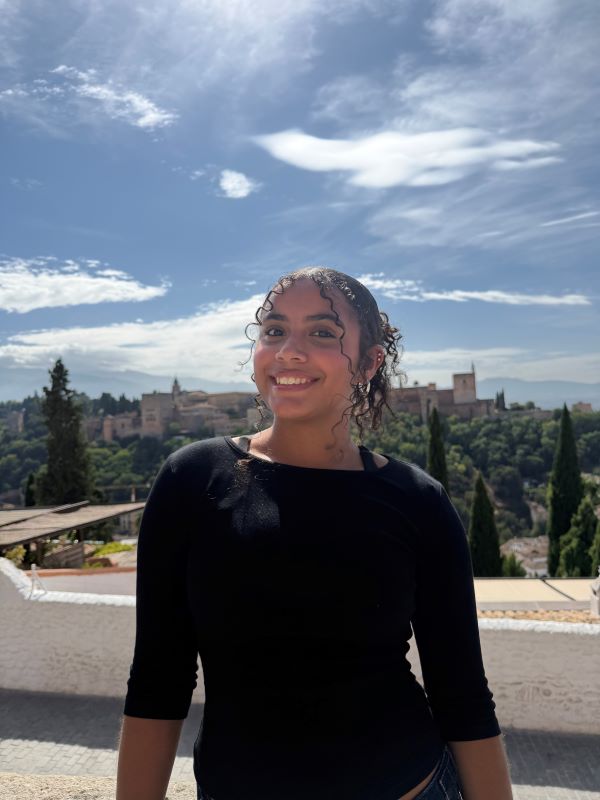 A study abroad student wearing a black shirt standing outdoors and smiling at the camera