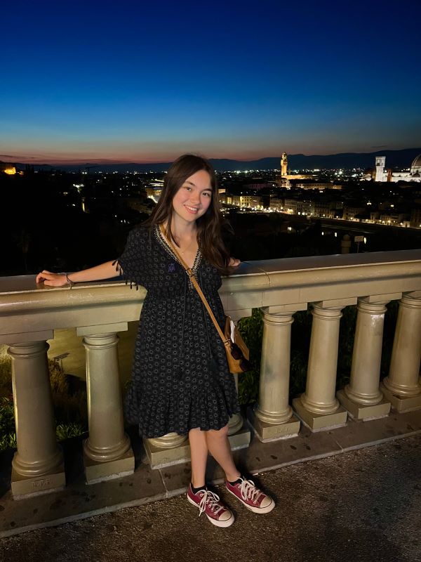 A study abroad student standing outdoors at night and smiling at the camera