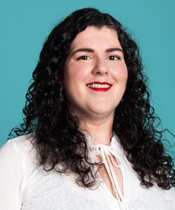 A person against a teal background smiling at the camera.