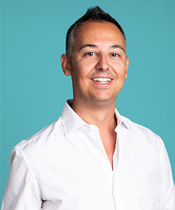 A person in front of a teal background smiling at the camera.