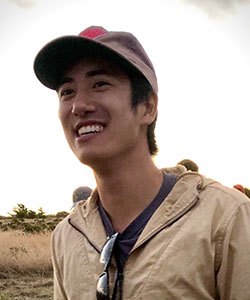 A person wearing a baseball hat smiling.